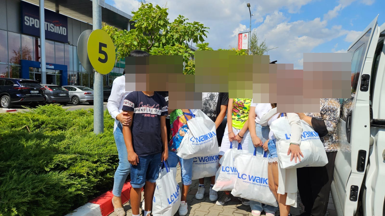 Copiii primind haine donate, cu fețele protejate